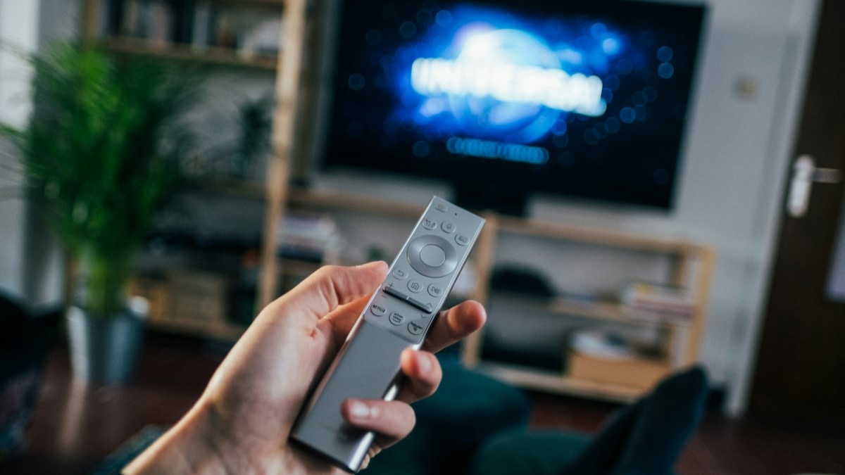 Android TV home screen on a television with a remote control in the foreground